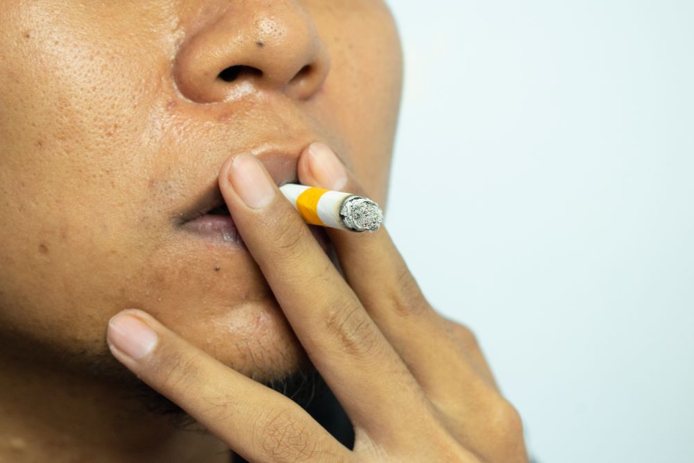 Unrecognizable person holding a cigarette to their lips