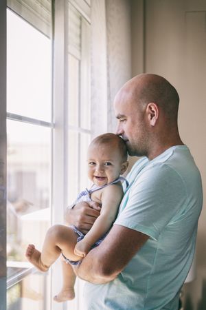 Father with baby looking out window