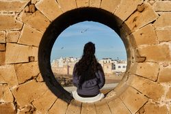 Woman sitting on stone monument near ancient town