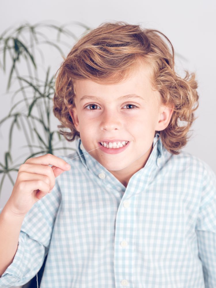 Cute preteen boy twitching tooth with thread