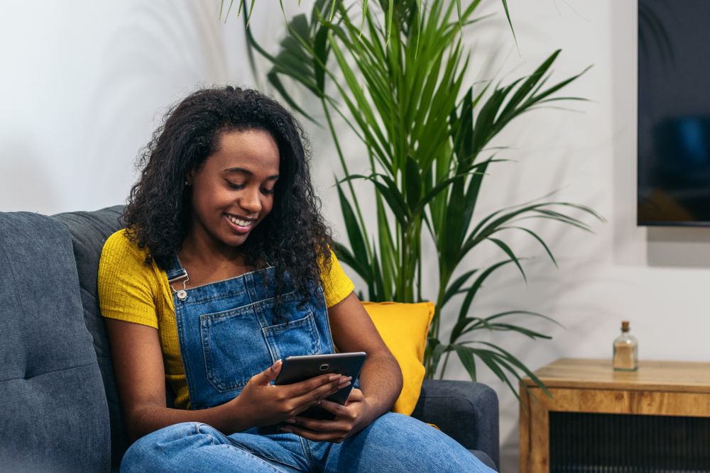 Digital Lifestyle: Young Black Woman Using Tablet at Home