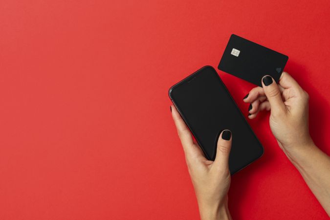 Female hands hold phone and card on red background