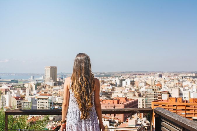 Woman on balcony looking at city views from above