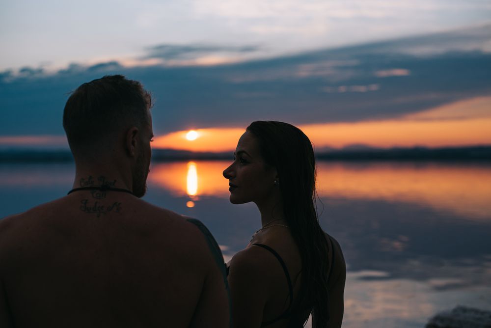 Couple hugging on beach of lake at sunset