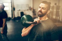 Man holding kettlebell to chest in class
