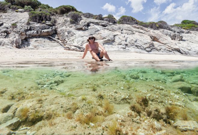 Man lying on sandy shore near water