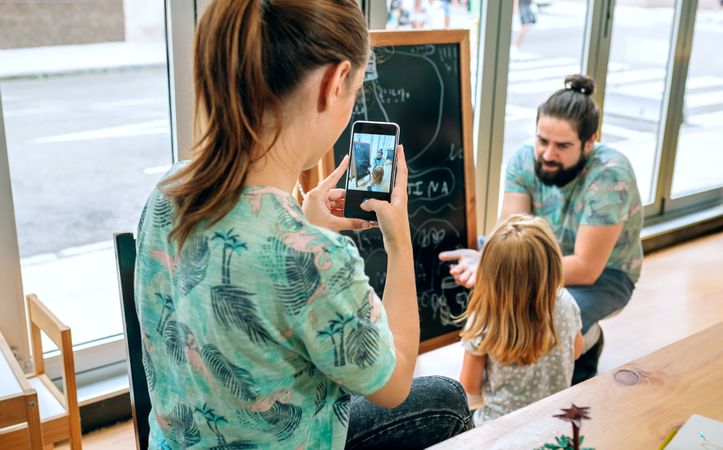 Family business owners taking break to teaching daughter and taking photos in their cafe restaurant