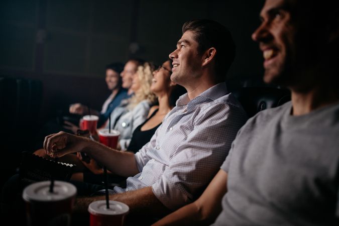 Young man watching movie with his friends in movie theater