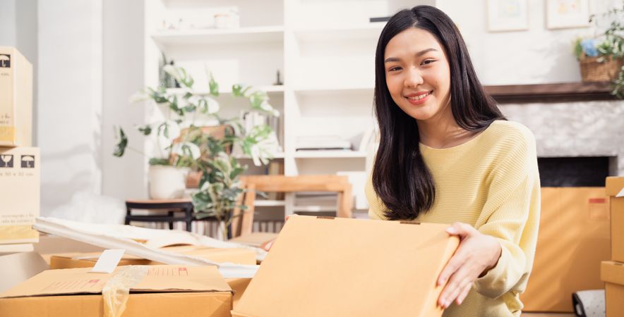 Asian smiling woman with cardboard boxes for moving to the new home