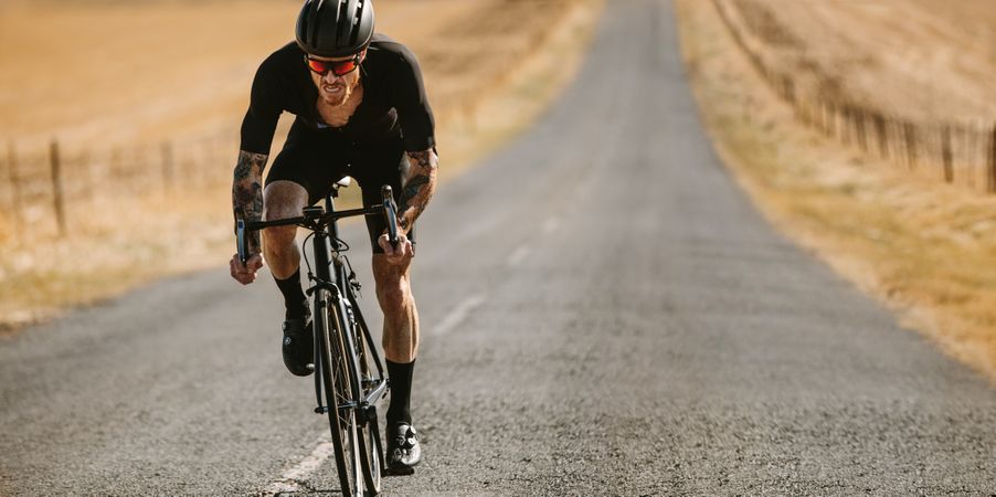 Professional athlete cycling on long countryside highway
