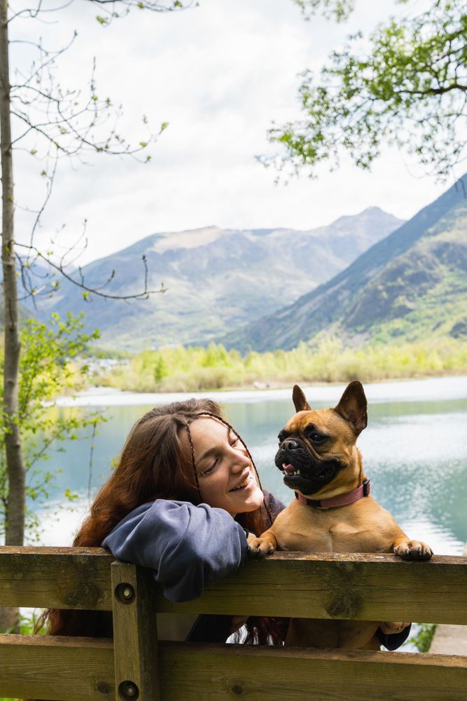 Female traveler with dog near lake in mountains