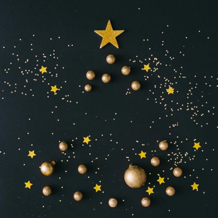 Golden decorations shaped in Christmas on dark table