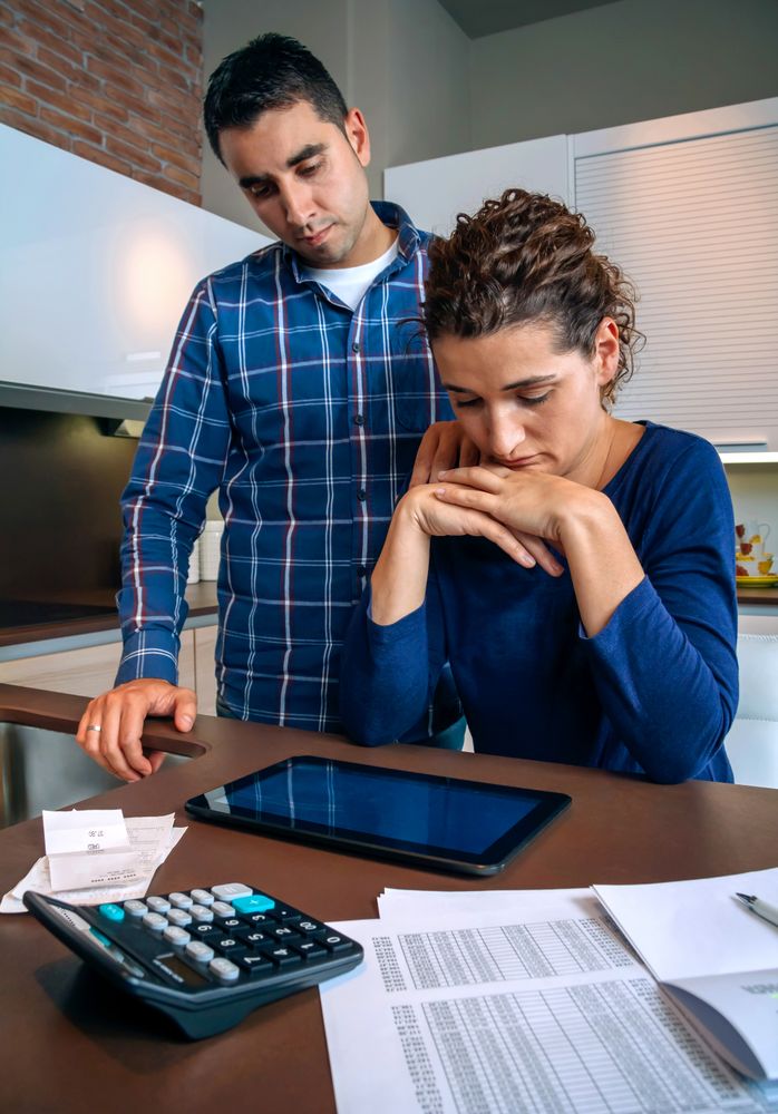 Strained couple going through their bills together in the kitchen, vertical