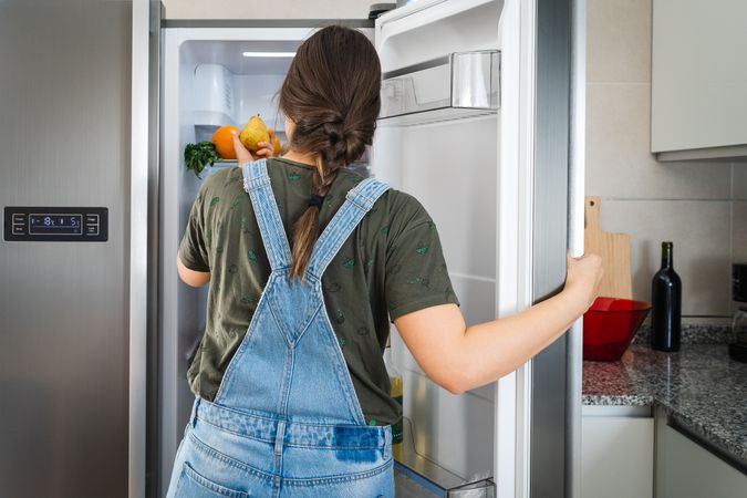 Crop woman taking fruit from fridge