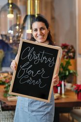 Cheerful female owner demonstrating chalkboard in flower shop