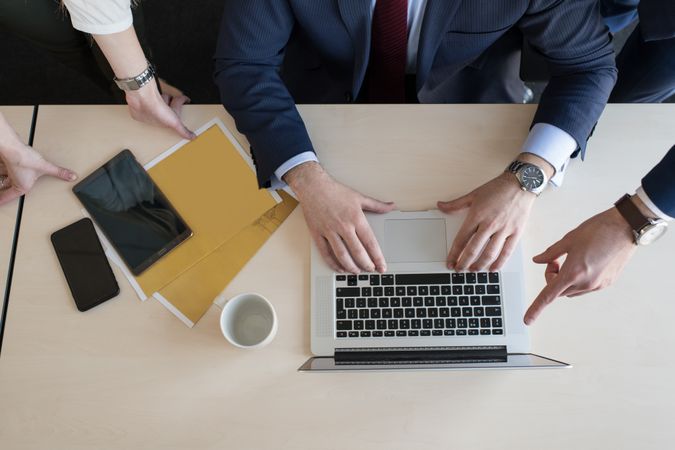 Stylish coworkers gathering around laptop in office