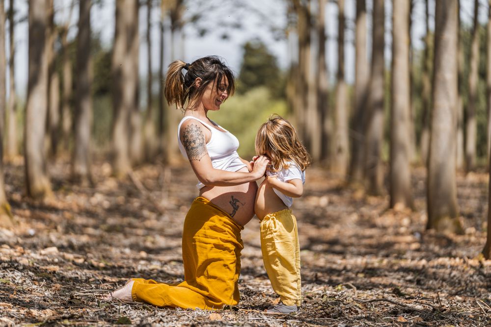 Pregnant mother and little daughter having fun in park