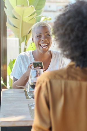 Smiling Black woman using smartphone in cafe