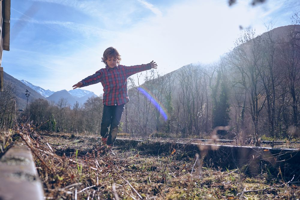 Boy balancing on rails among bare trees