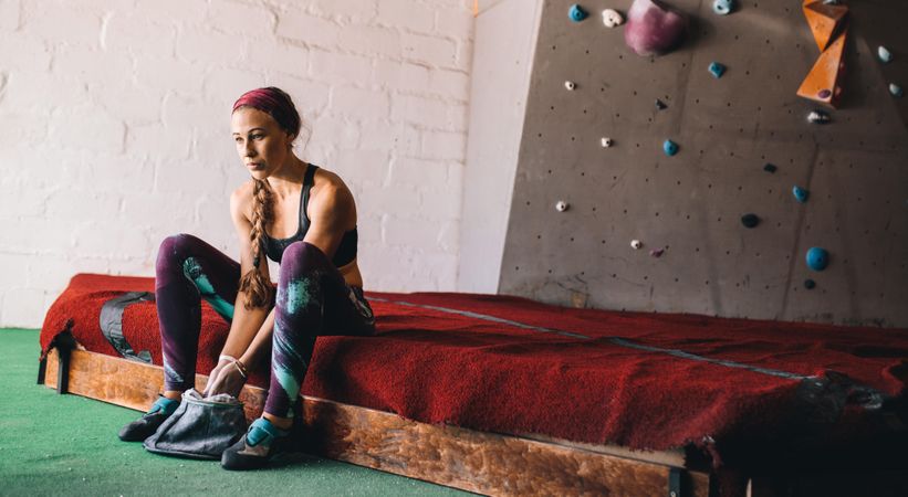 Athletic female wearing climbing gear and preparing hands for climbing