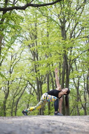 Woman in colorful exercise gear stretching in the forest