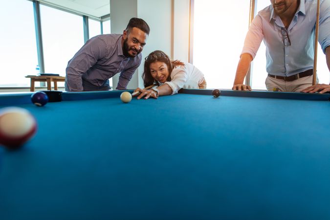 Low angle of group of playful colleagues playing pool
