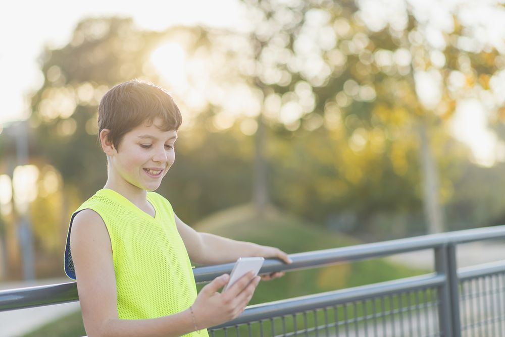 Portrait of a teenager smiling looking his smartphone