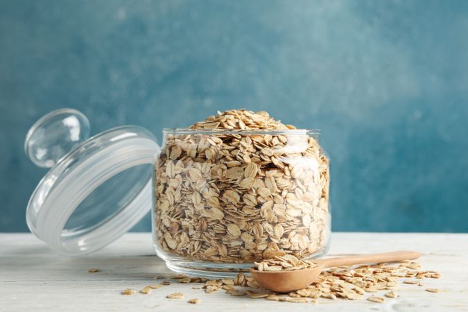 Glass jar with oatmeal and spoon on blank wooden table
