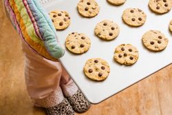 Woman holding a tray with baked cookies with kitchen gloves