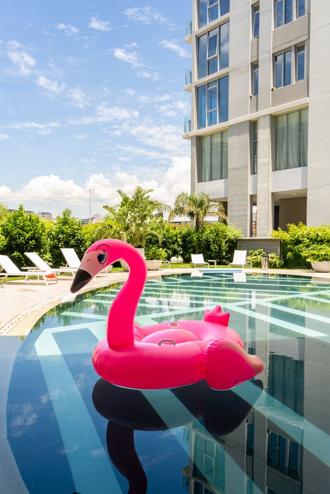 A pink flamingo pool float is floating in a pool. Vertical shot