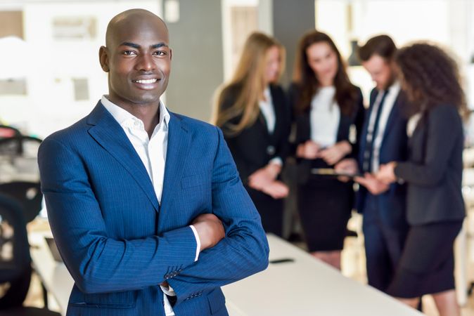 Black businessman standing in foreground of busy office