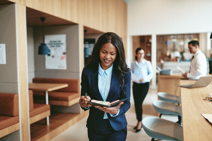 Woman with open note book standing in office