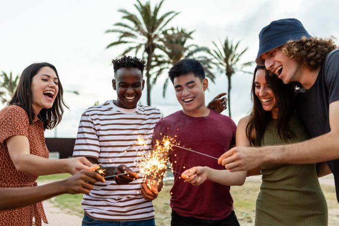 Happy multiracial people laughing and having fun together with sparkles outdoors
