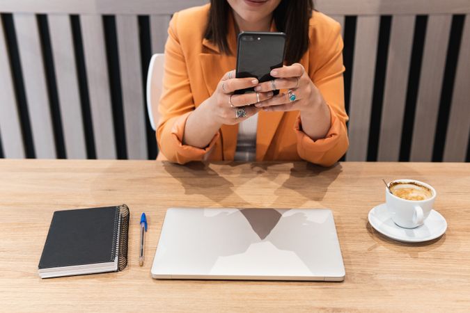 Anonymous woman using smartphone and working in cafe