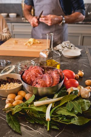 Unrecognizable man peeling vegetables at table with raw octopus
