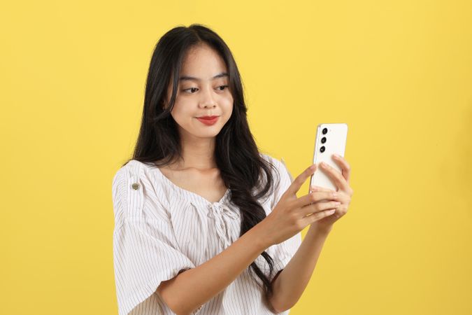 Happy Young Asian Woman using Mobile Phone or Touching Screen Application on Smartphone