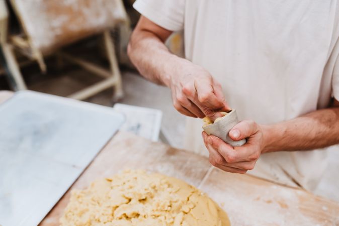 Unrecognizable cook putting pastry dough in cup