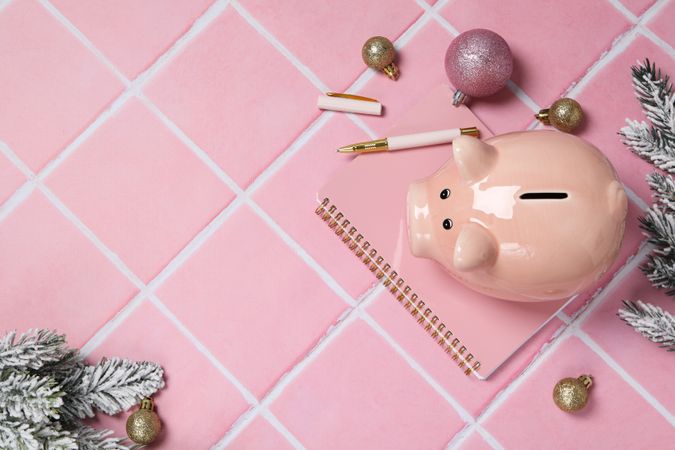 Piggy bank, Christmas decor and notepad on pink background, space for text