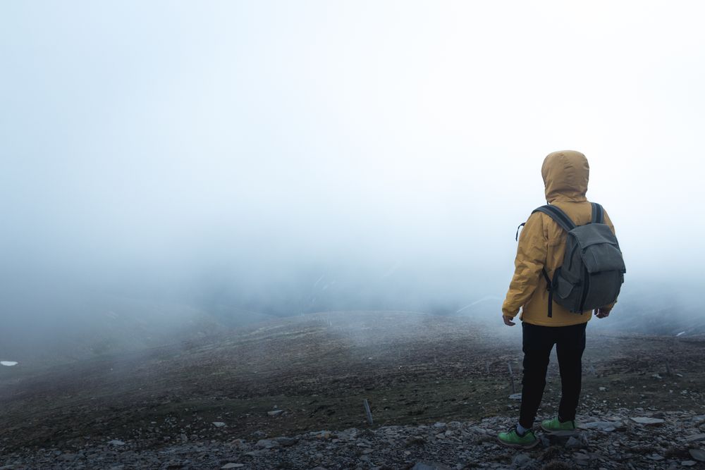 Anonymous traveler on hill on misty day