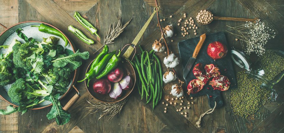 Assortment of seasonal winter vegetables, pomegranates, peppers, broccoli on wooden table
