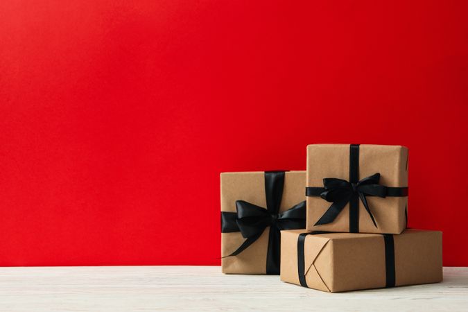 Gift boxes on wooden table against red background