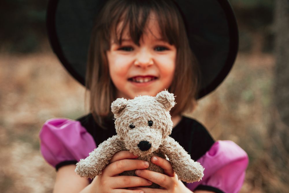 Smiling girl with teddy bear in halloween costume