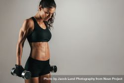 Athletic woman resting with weights at her sides bGR3yv