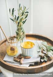 Morning turmeric latte in ceramic cup with honey in glass 5QRad4