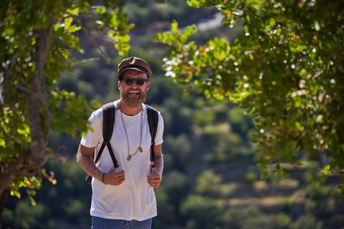 Smiling male traveler with backpack in forest