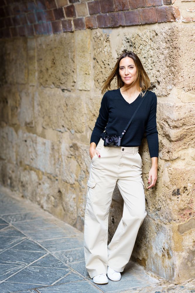 Woman with camera leaning on wall outside in old town