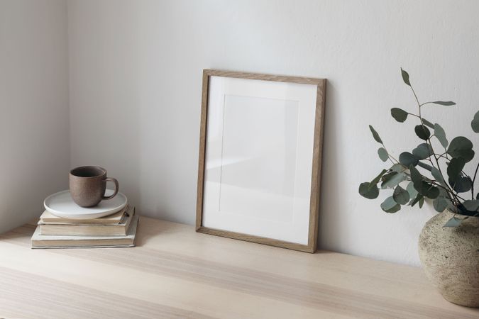 Cup of coffee, books. Empty wooden picture frame mockup on desk,