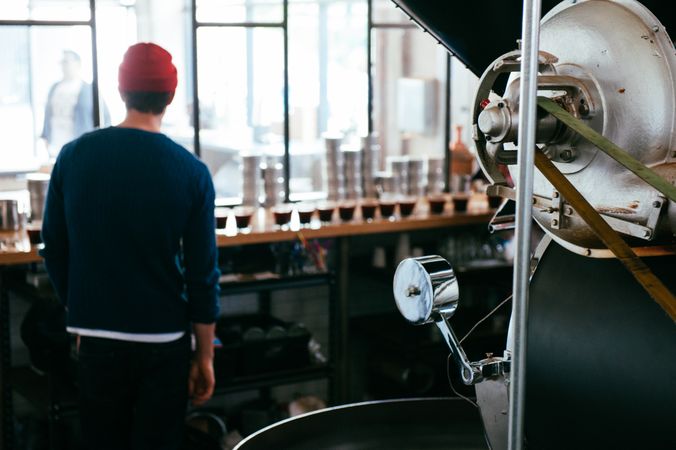 Back view of coffee roaster master looking into coffee shop with glasses for tasting