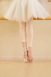 Ballet dancer at barre with one foot in pointe shoes