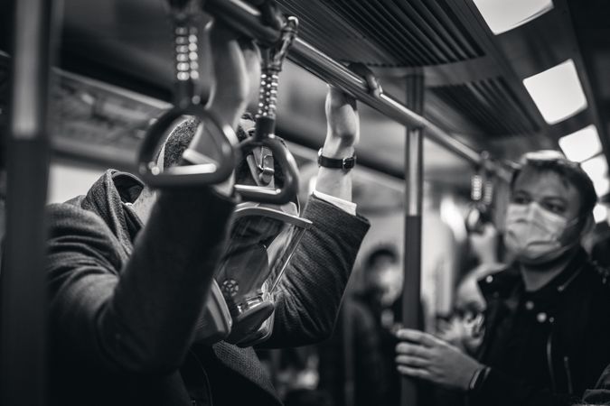 Grayscale photo of men wearing facemasks and gas masks in train